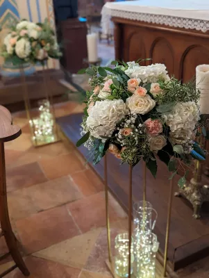 Grande composition florale d'allee avec hydrangeas blancs, roses peches et feuillage vert pour mariage classique.