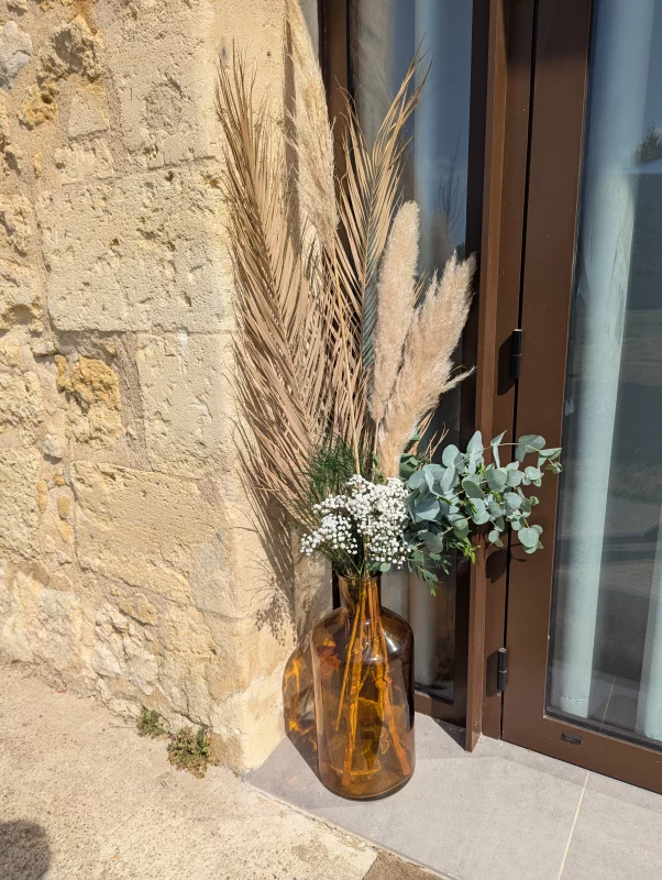 Bohemian floral composition with pampas grass, eucalyptus and dried palm leaf in an amber vase.