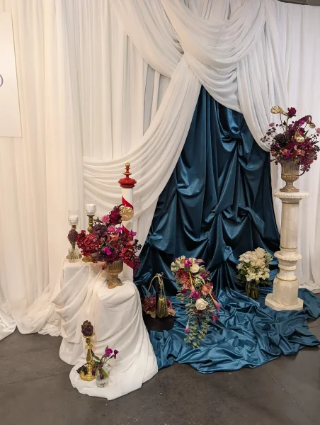 Scénographie florale classique et exotique avec roses bordeaux, anthuriums dorés et orchidées magenta pour un salon du mariage à Bordeaux.