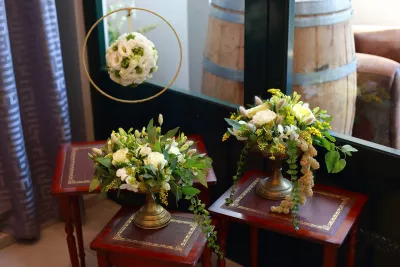 Scénographie bohème élégante avec roses jaunes et blanches, freesias, feuillage et pampas.