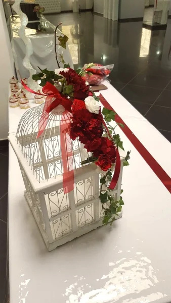 Composition florale classique avec roses rouges et blanches, œillets et lierre sur une cage décorative blanche, mariage.
