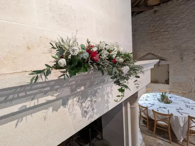 Composition florale champêtre sur la cheminée, avec roses blanches et rouges, alstroemeria, gypsophile et feuillages divers.