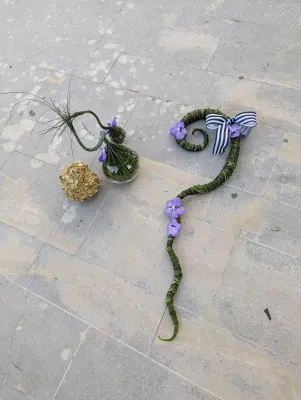 Two modern, sculptural floral designs with purple Vanda orchids and green foliage.