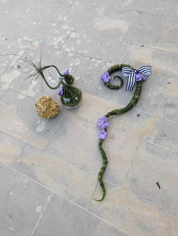 Two modern, sculptural floral designs with purple Vanda orchids and green foliage.