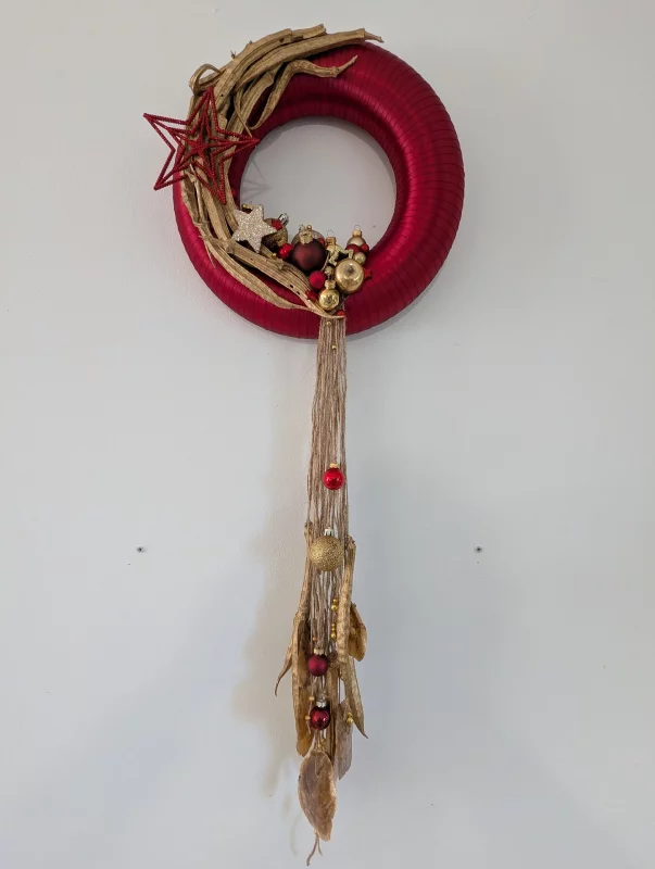 Couronne décorative de mariage de style bohème avec branches et feuilles séchées, accents dorés et rouges, ambiance automnale.