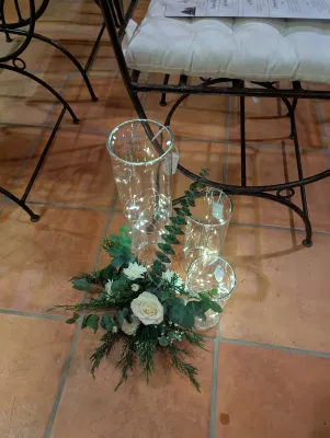 Décoration d'allée de cérémonie avec roses blanches, chrysanthèmes et verdure dans des vases lumineux, style classique.