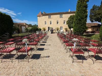 Décoration d'allée champêtre pour cérémonie de mariage, avec petits bouquets de gypsophile sur chaises rouges.