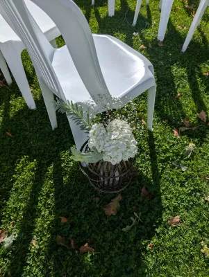 Décoration d'allée de cérémonie champêtre avec hortensias blancs, gypsophile et feuillage dans une cage métallique rustique, posée au sol.
