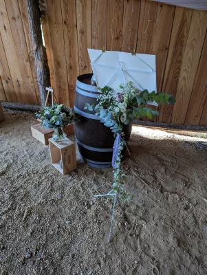 Décoration de coin champêtre sur baril en bois avec roses, gypsophile et feuillage pour un mariage.
