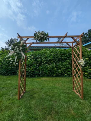 Décoration florale d'arche en bois pour mariage, avec eucalyptus, roses blanches, gypsophile et herbe de la pampa.