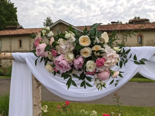 Arche florale classique décorée d'hortensias, pivoines roses et roses pour un mariage en extérieur au Château Grattequina.