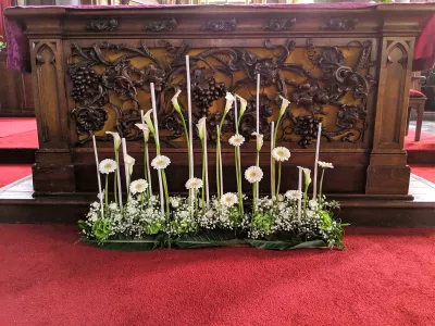 Décoration d'autel de mariage classique, avec des rangées d'arums, gerberas et gypsophile entourant des bougies hautes.