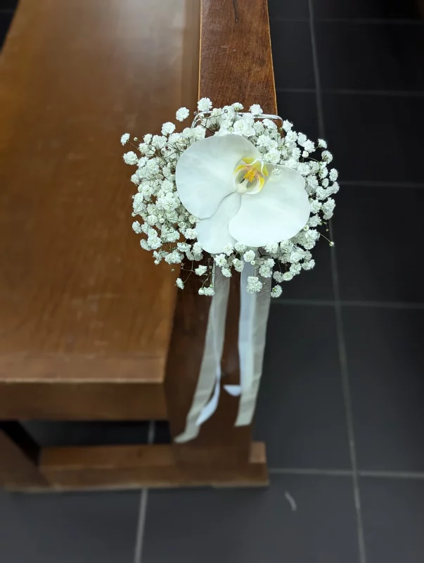 Classic wedding ceremony bench decoration with a single white orchid and gypsophila.