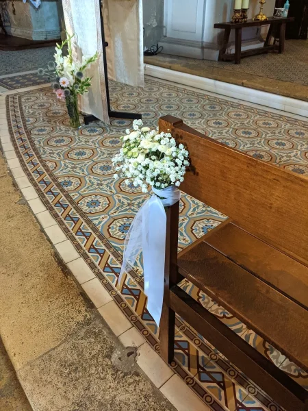 Décoration de bancs de cérémonie mariage bohème avec petits bouquets de gypsophile blanc et rubans sur les pews.