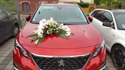 Décoration florale de capot de voiture style classique avec des orchidées blanches, des roses crème et roses, et du feuillage vert.