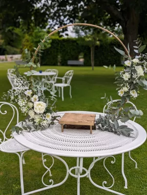 Décoration de cérémonie avec cercle doré orné de roses blanches, gypsophile et eucalyptus, style classique.