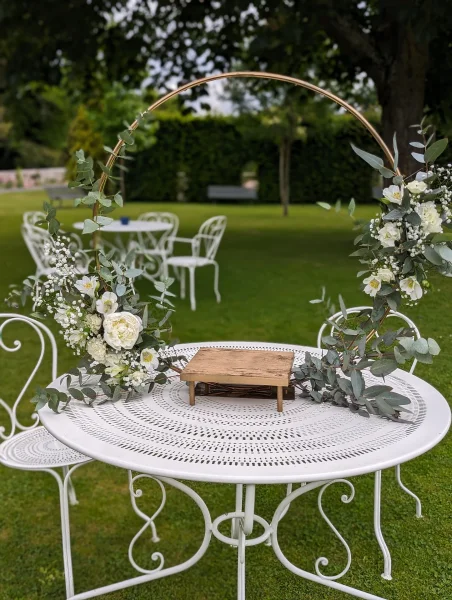 Décoration de cérémonie avec cercle doré orné de roses blanches, gypsophile et eucalyptus, style classique.
