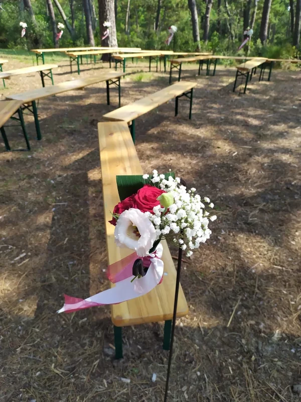 Décoration d'allée de cérémonie style champêtre avec roses rouges, gypsophile et eustoma, pour un mariage.