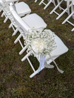 Décoration de chaise de cérémonie champêtre avec couronne de gypsophile et œillet blanc pour un mariage.