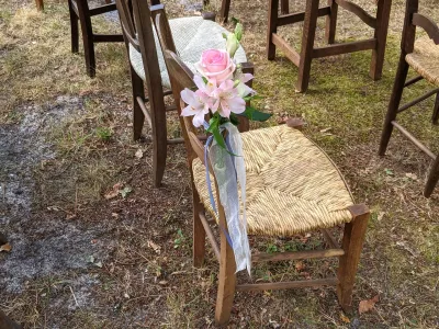 Décoration de chaise champêtre pour cérémonie, avec une rose rose pâle, des alstroemeria blanches et un ruban bleu clair.