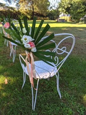 Gros plan sur la décoration de chaises de cérémonie avec feuilles de palmier, roses roses et eustoma blanc