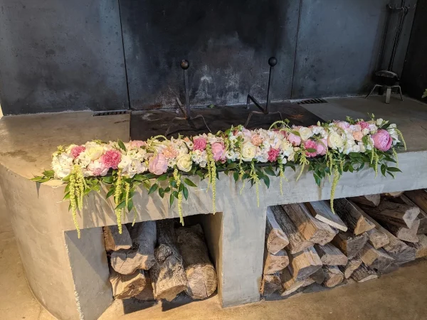 Décoration florale de cheminée style classique avec roses et œillets roses, créant une ambiance élégante pour un mariage.
