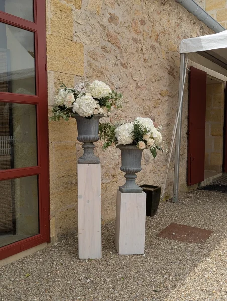Deux colonnes décoratives avec compositions florales d'hortensias blancs et roses, idéales pour un mariage champêtre ou classique en extérieur.