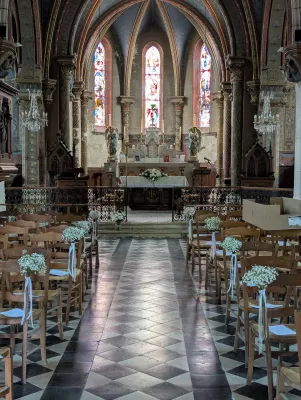 Décoration d'allée de cérémonie de mariage dans une église, avec des bouquets de gypsophile et rubans blancs sur les chaises.