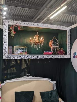 Décoration murale encadrée avec chandelier suspendu, petite composition florale et boîte 'Merci', style vintage élégant.