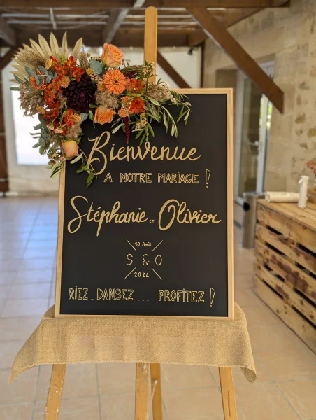 Decoration florale boheme pour panneau de bienvenue de mariage avec roses peches, pampas et dahlia prune.