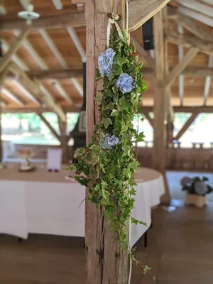 Décoration de pilier champêtre avec du lierre tombant et des hortensias bleus, pour un mariage estival en intérieur.
