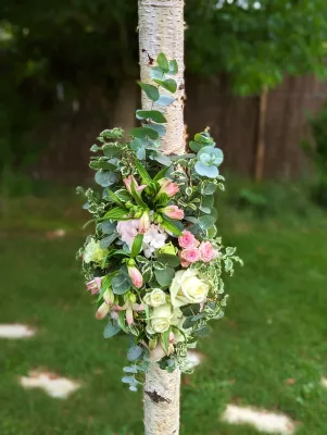 Détail d'une décoration florale champêtre sur pilier d'arche, avec roses blanches, roses pâles, alstroemerias et eucalyptus.
