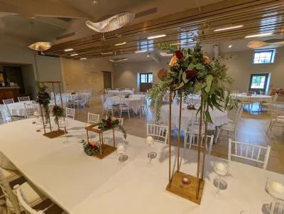 Décoration de salle de mariage bohème avec roses pêche et bordeaux, eucalyptus, sur structures bois et bougies.