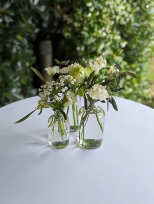 Décoration de table champêtre avec des vases en verre contenant alstroemeria, gypsophile et eucalyptus frais.