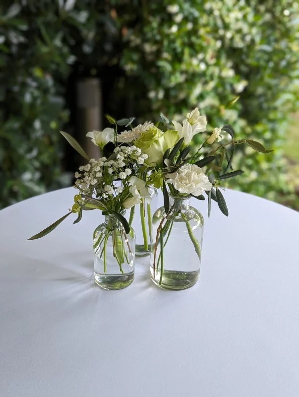 Décoration de table champêtre avec des vases en verre contenant alstroemeria, gypsophile et eucalyptus frais.