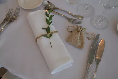 Détail de décoration de table pour mariage bohème, avec une feuille d'eucalyptus et cordelette sur une serviette blanche.
