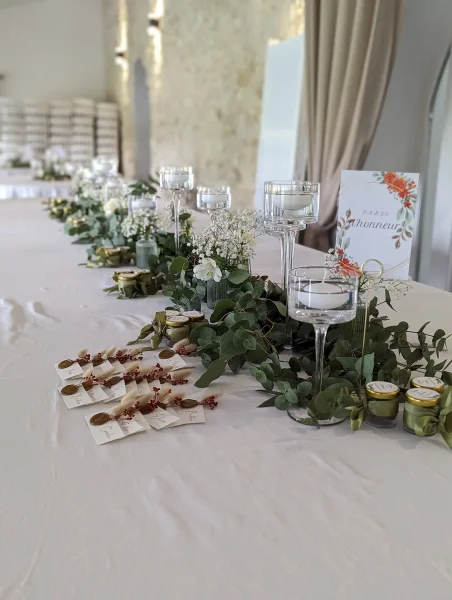 Détail de la décoration florale de la table d'honneur avec eucalyptus, gypsophile et roses blanches.