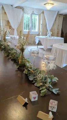 Décoration florale de table d'honneur bohème avec un chemin d'eucalyptus, delphinium et gypsophile.