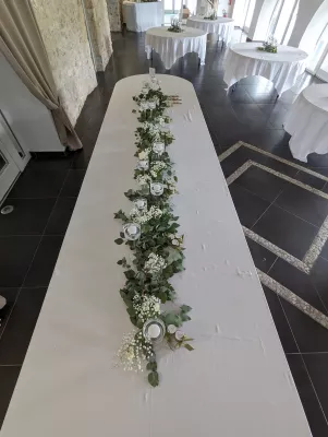 Longue guirlande florale avec eucalyptus, gypsophile et fleurs blanches pour la table d'honneur, style champêtre.