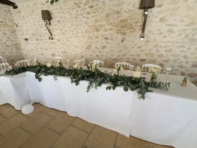 Décoration de table d'honneur champêtre avec une longue guirlande d'eucalyptus, roses et gypsophile.
