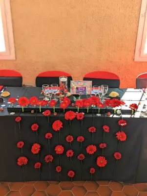 Décoration de table d'honneur moderne avec une cascade de gerberas rouges vifs, créant un impact visuel audacieux pour le mariage.