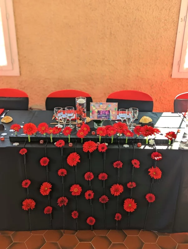 Modern top table decoration with a cascade of vibrant red gerberas, creating a bold visual impact for the wedding.