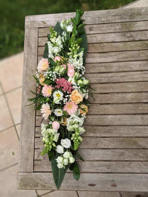 Décoration de table de mariage style champêtre, chemin de fleurs roses, blanches et pêche avec roses, gerberas et lisianthus.