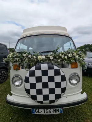 Décoration florale pour véhicule de mariage, une guirlande de fleurs blanches et feuillage sur un van vintage, style champêtre.