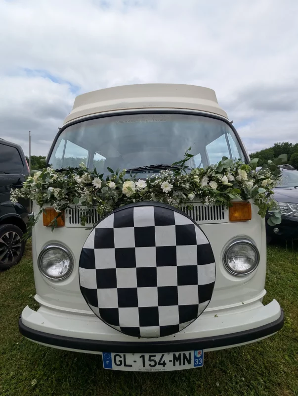 Wedding vehicle floral decoration, a garland of white flowers and foliage on a vintage van, country style.