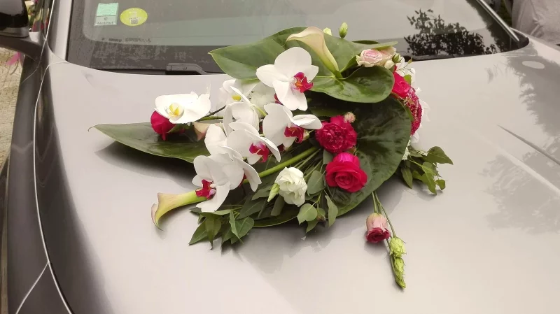 Classic wedding car decoration, featuring white orchids, fuchsia roses and calla lilies.