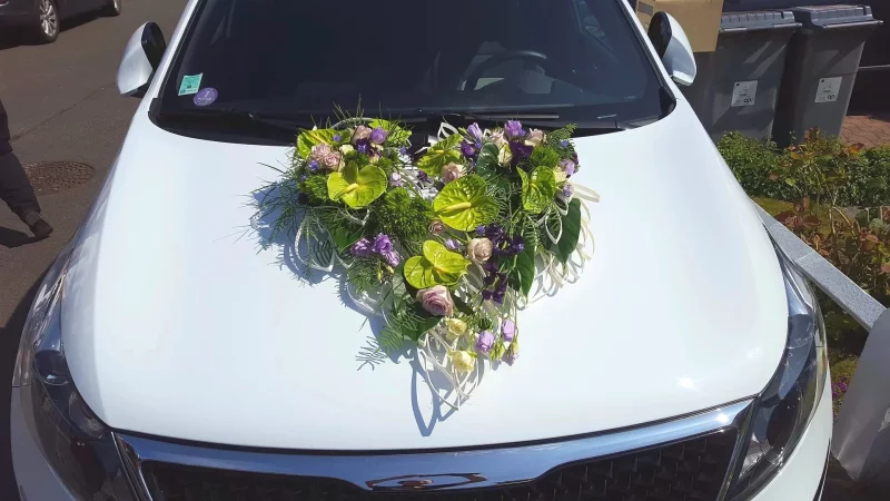 Décoration de voiture de mariage classique et exotique en forme de cœur avec anthurium vert lime, roses roses et lisianthus violets.