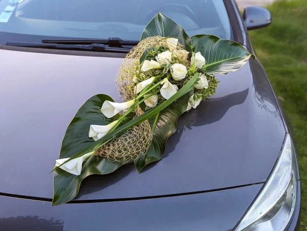 Décoration de voiture moderne pour le mariage de Cynthia, composée d'arums blancs, roses et grands feuillages verts.