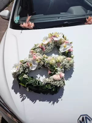 Grande décoration de voiture de mariage en forme de cœur avec orchidées blanches, roses et gypsophile pour l'été.