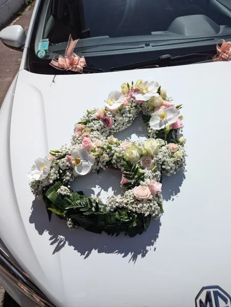 Grande décoration de voiture de mariage en forme de cœur avec orchidées blanches, roses et gypsophile pour l'été.